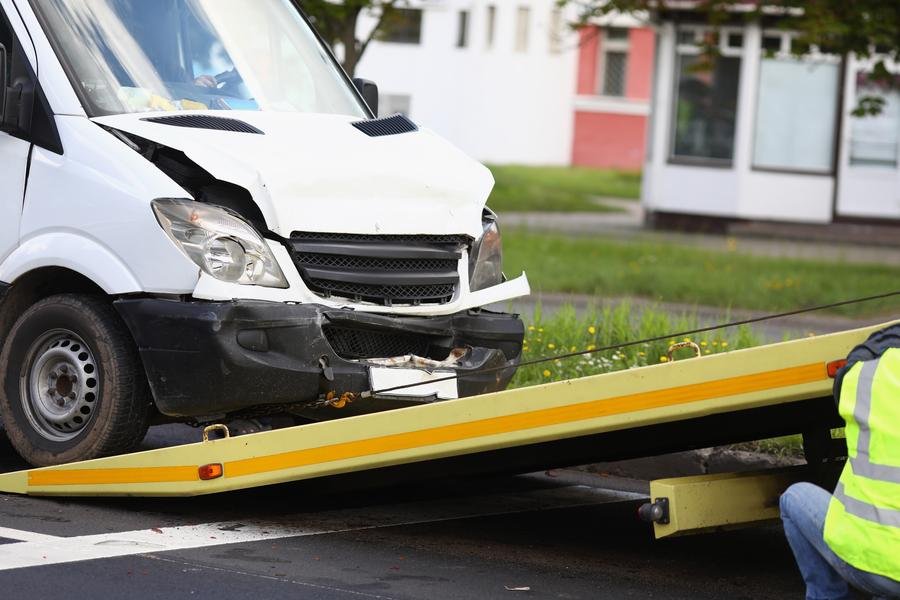 Van damaged in an accident being pulled onto a flatbed tow truck