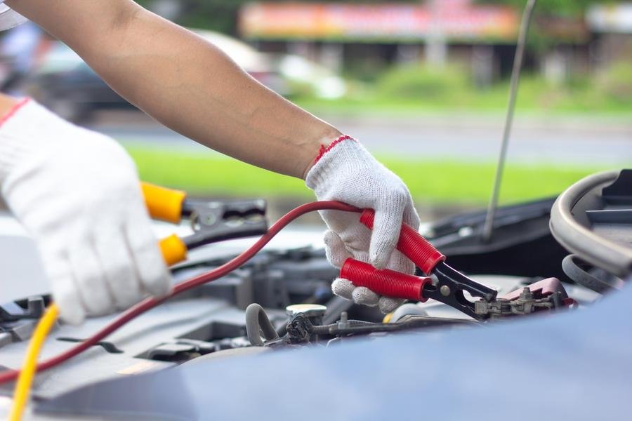 Roadside assistance operator boosting a dead car battery with jumper cables