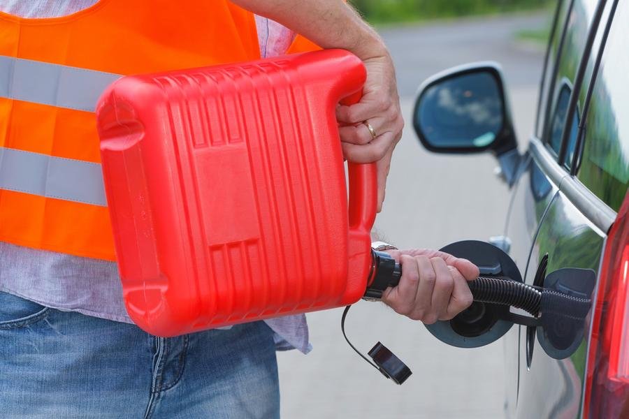 Tow operator filling a car's gas tank from a jerry can after it ran out of fuel